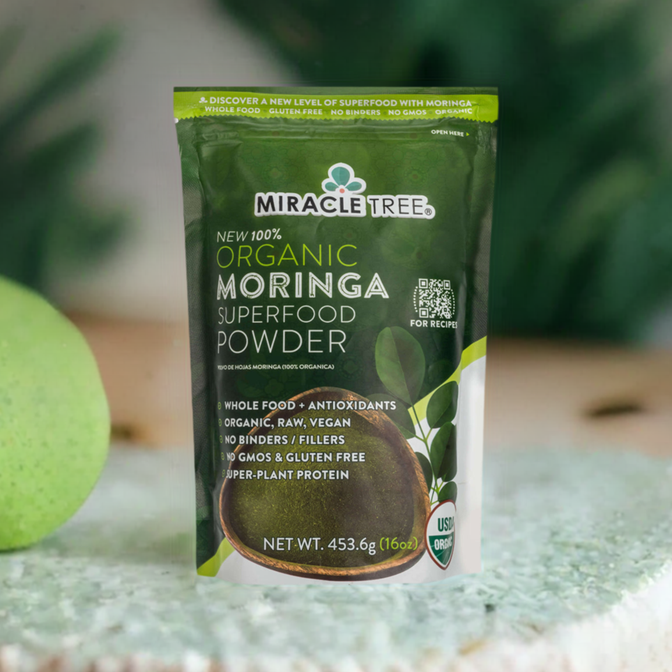 
                  
                    A Miracle Tree 100% Organic Moringa Pouch, in green, rests on a table near a blurred apple. The packaging emphasizes its an organic superfood—raw, vegan, gluten-free—and rich in protein and antioxidants.
                  
                